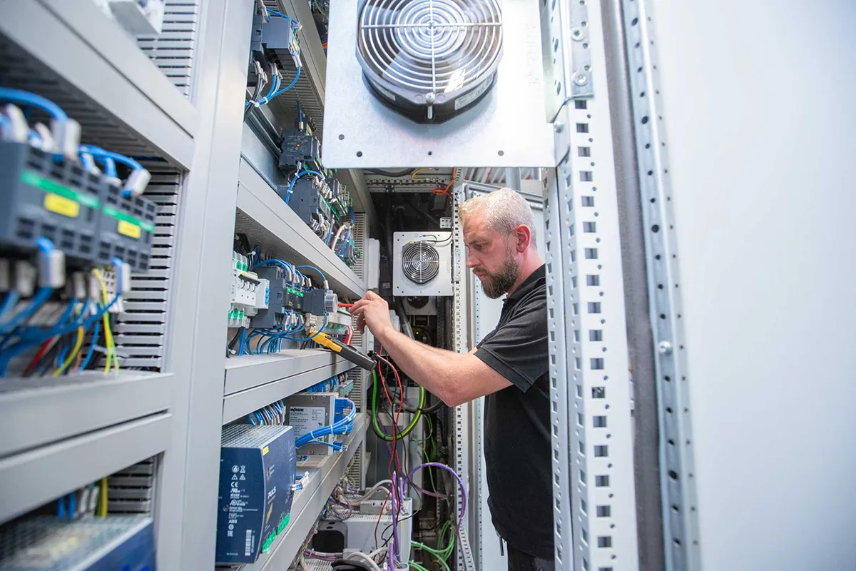 Mitarbeiter prüft elektrische Komponenten in einem geöffneten Schaltschrank