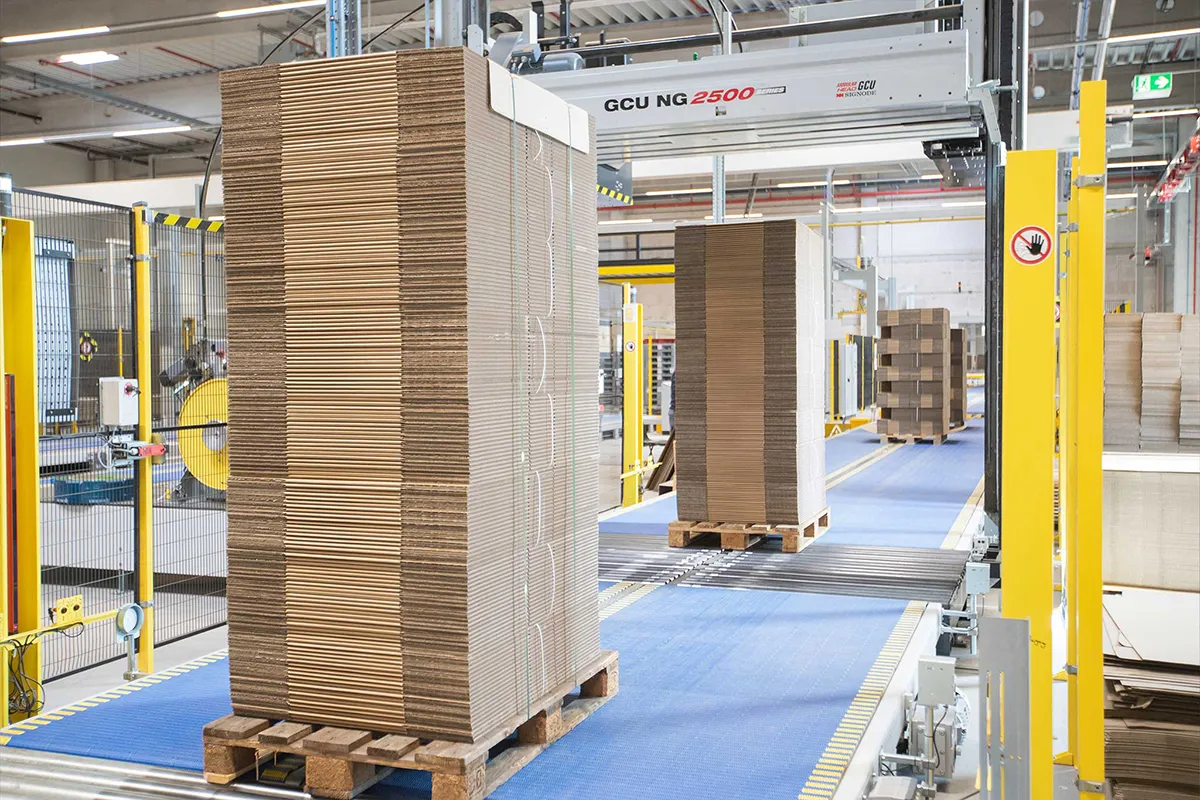 Gestapelte Wellpappkartons auf Paletten in der Produktionshalle
